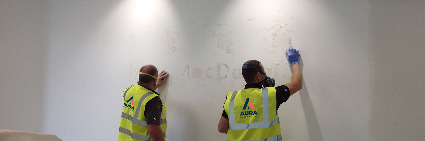 Team carrying out surface repairs, preparation and paint for new signage to wall