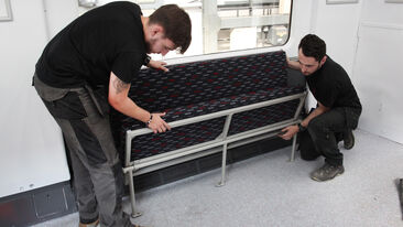 Two men fit and secure new carriage seat