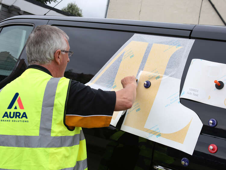 Man applying branded graphics onto Addison Lee vehicle